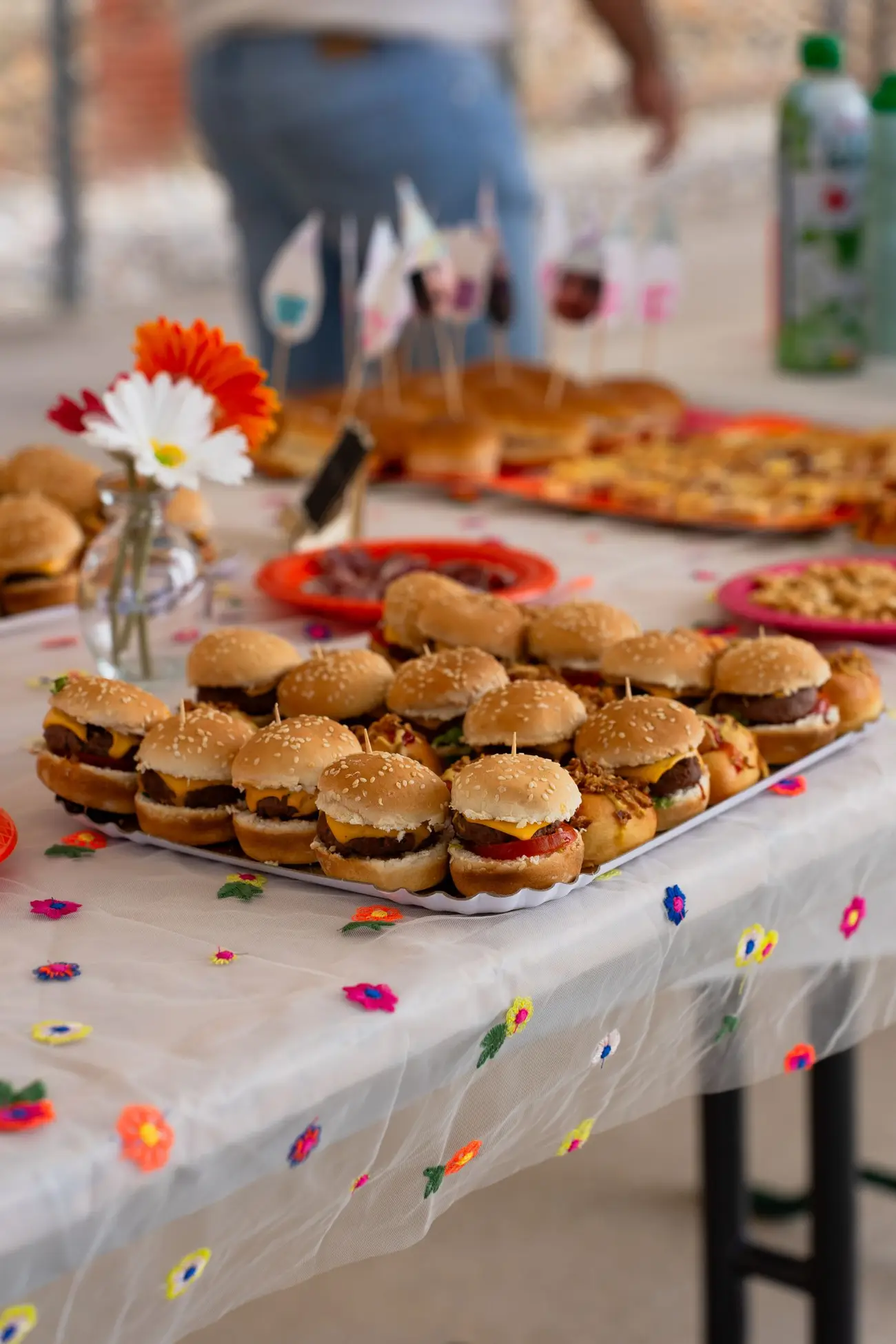 Mini burgers arranged on a colourful outdoor celebration table