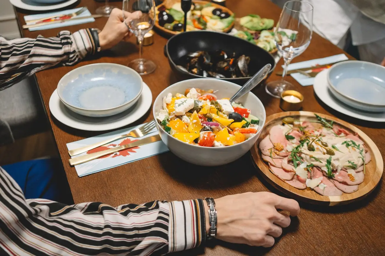 A table shared with colourful dishes and guests, illustrative photography