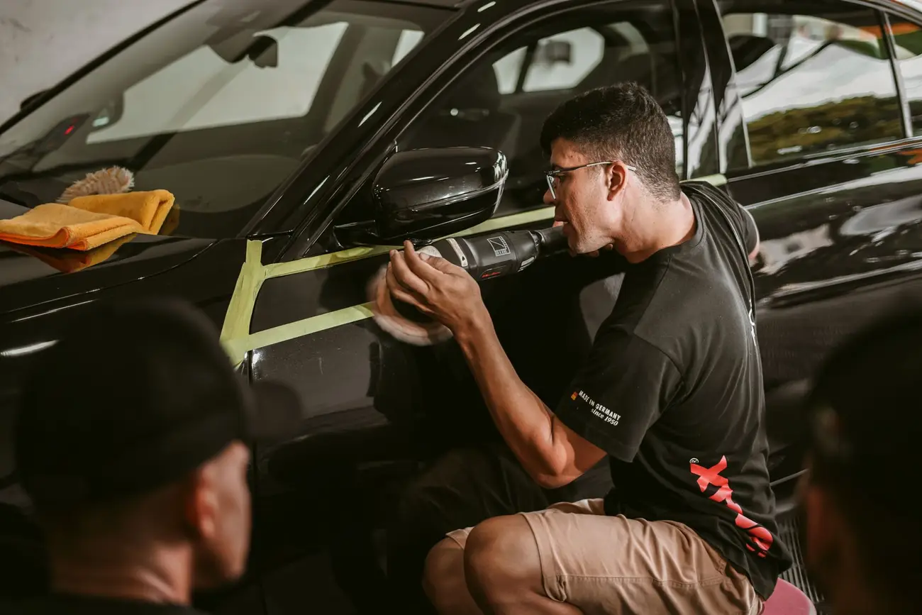 Detailer polishing the side panel of a dark car