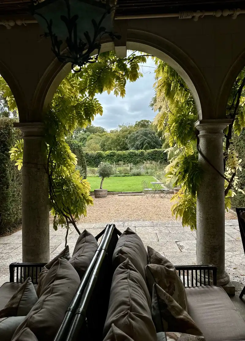 Stone arched patio overlooking a lawn and planted borders