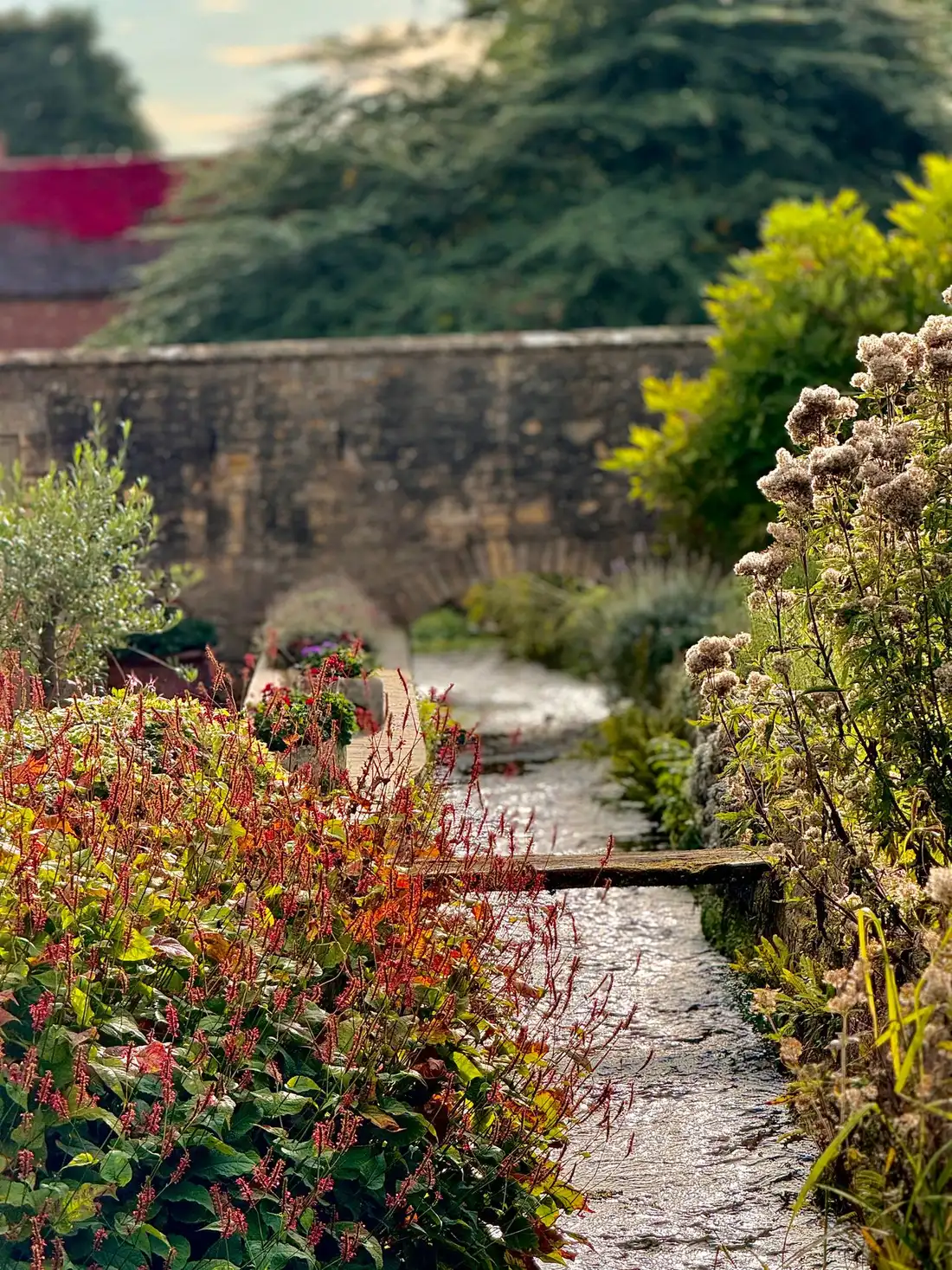 Stone garden path bordered by perennials and a weathered wall