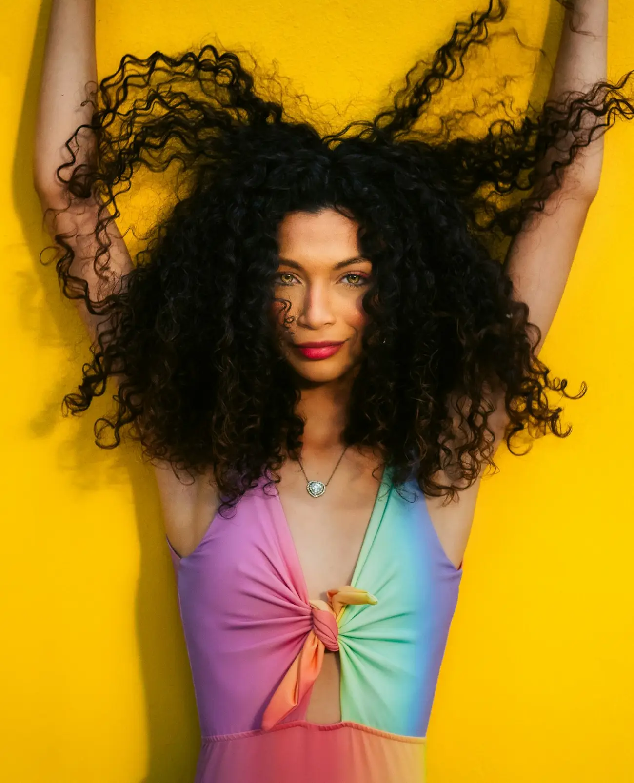 Portrait with long voluminous curls against a yellow backdrop