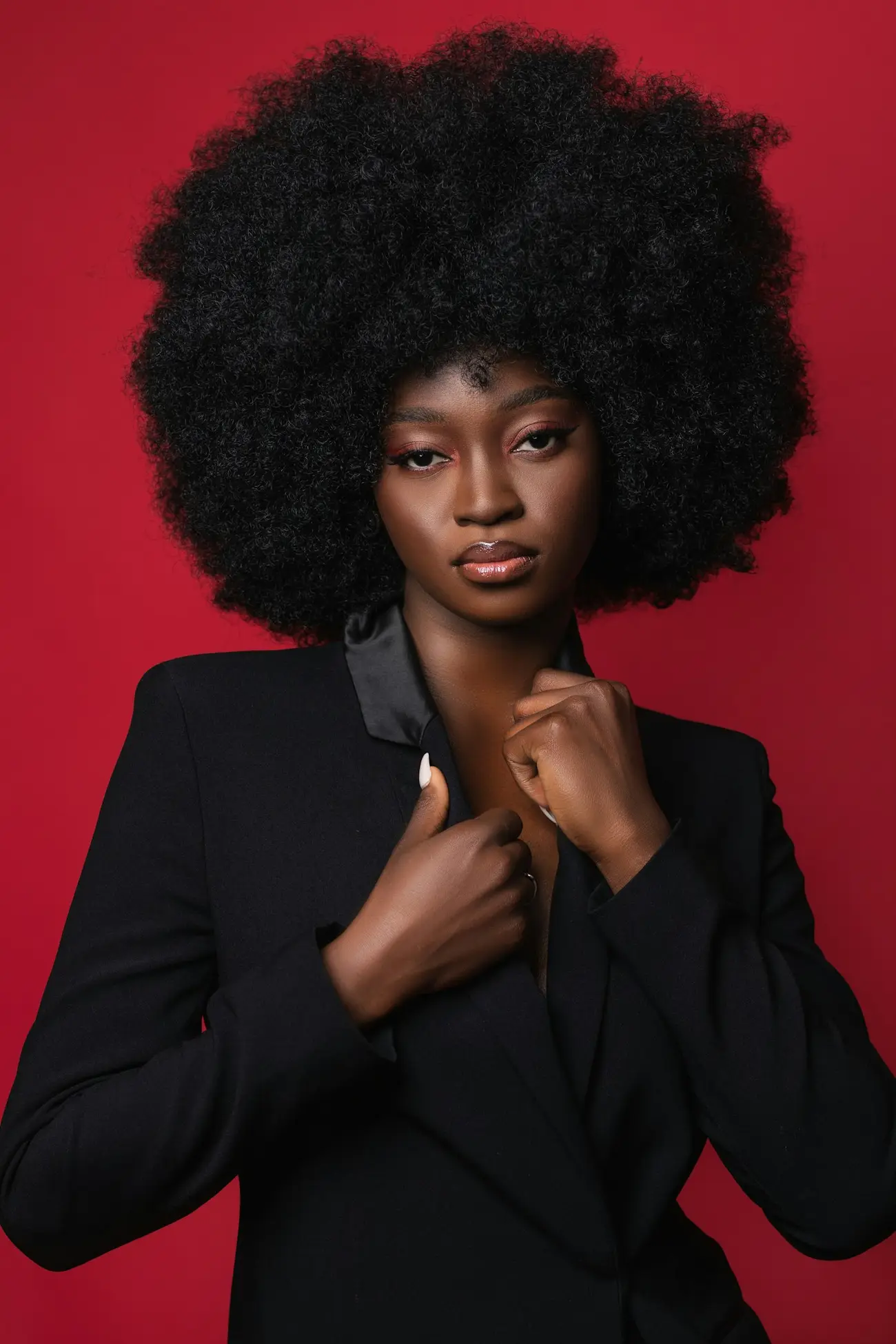 Editorial portrait with a full natural afro against a red backdrop